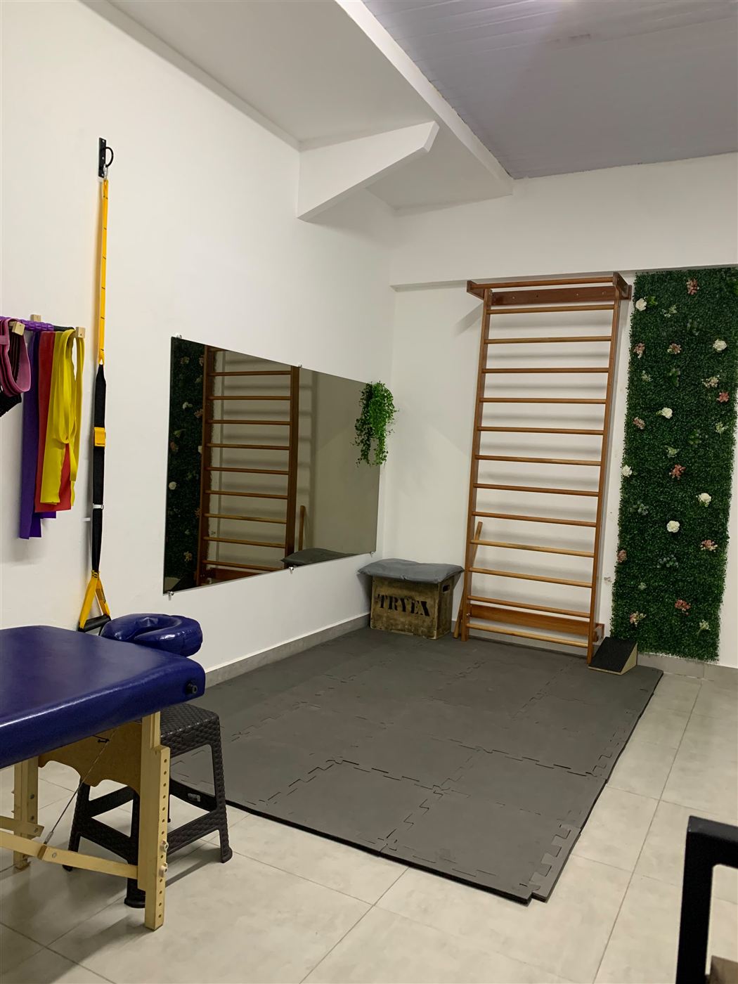 Sala de fisioterapia com espaldar, maca e espelho